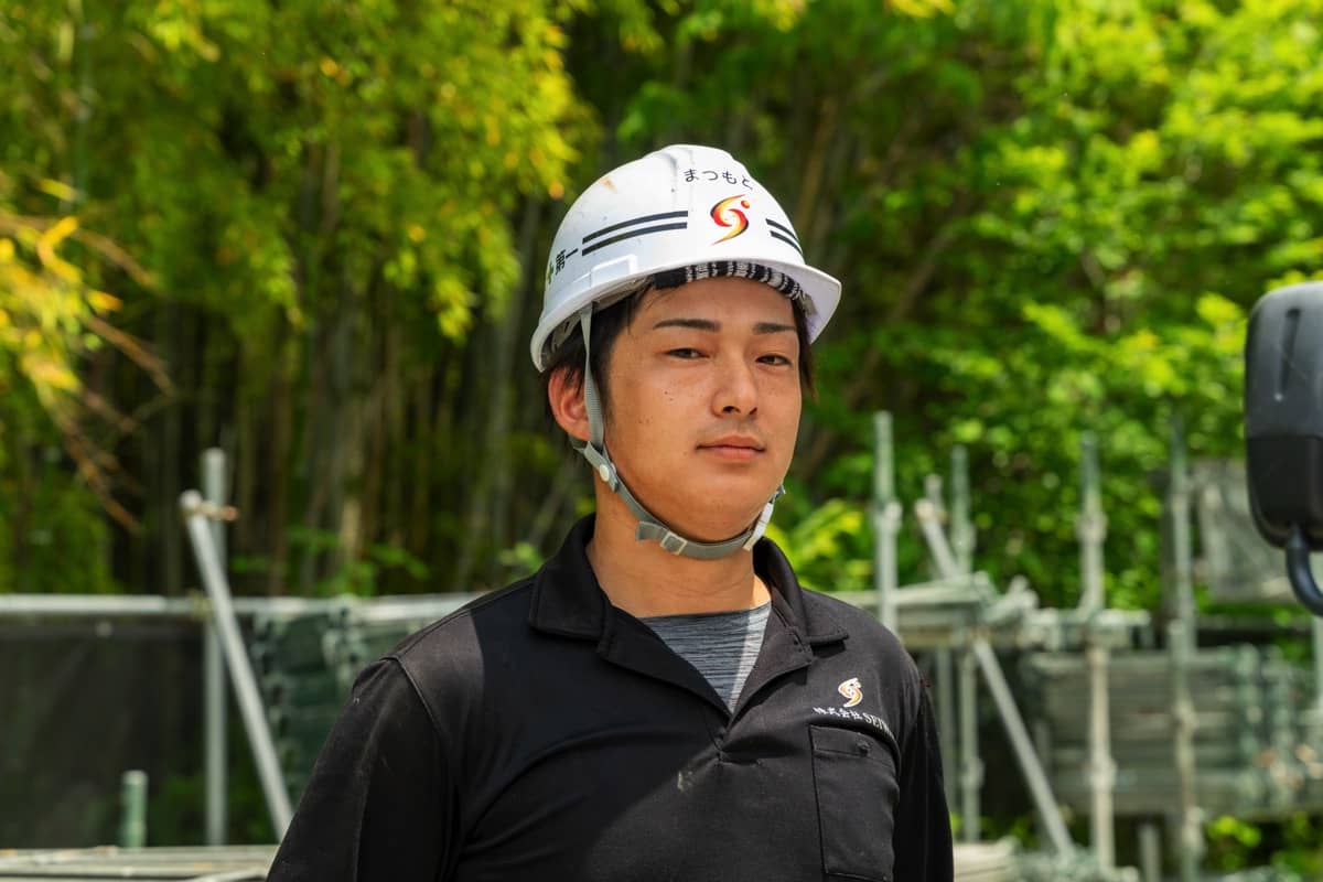 足場の前でポーズを決めるスタッフ